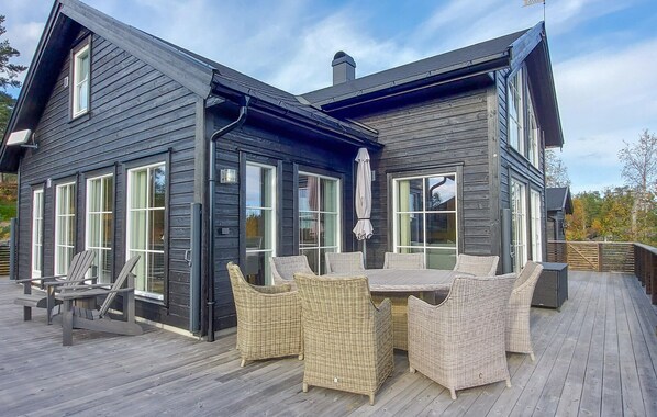 A two-story wooden house with large windows and a deck with wicker furniture. - 4 bedroom cozy home in Skollenborg (Skollenborg)