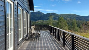 Eine Holzterrasse mit Blick auf einen bewaldeten Gebirgszug.