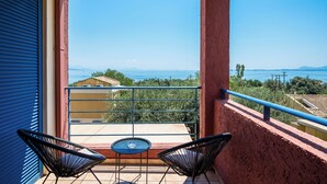 A balcony with two chairs and a small table, overlooking a scenic view of the sea and distant mountains. - Akti Barbati Houses by Konnect - Two-Bedroom Maisonette (Corfu)