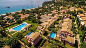 An aerial view of a coastal resort with multiple villas, a central swimming pool, and a beach. - Akti Barbati Houses by Konnect - Two-Bedroom Maisonette (Corfu)