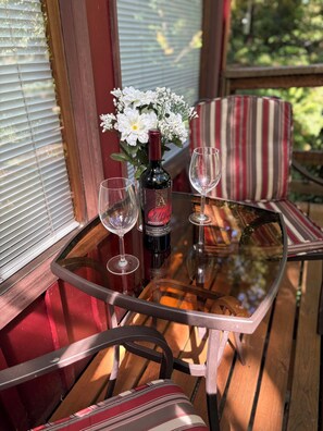 A glass table with a bottle of wine and two wine glasses on a wooden deck. - ‘Volcano Country’ Creek side Cottage in Doty (Chehalis)
