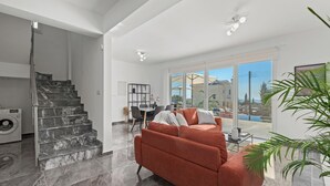 A modern living area with a staircase, a red sofa, and a dining area.