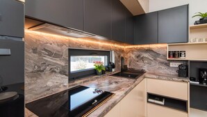 A modern kitchen with a black countertop, marble backsplash, and built-in appliances. - Luxurious home in Razanac (Razanac)