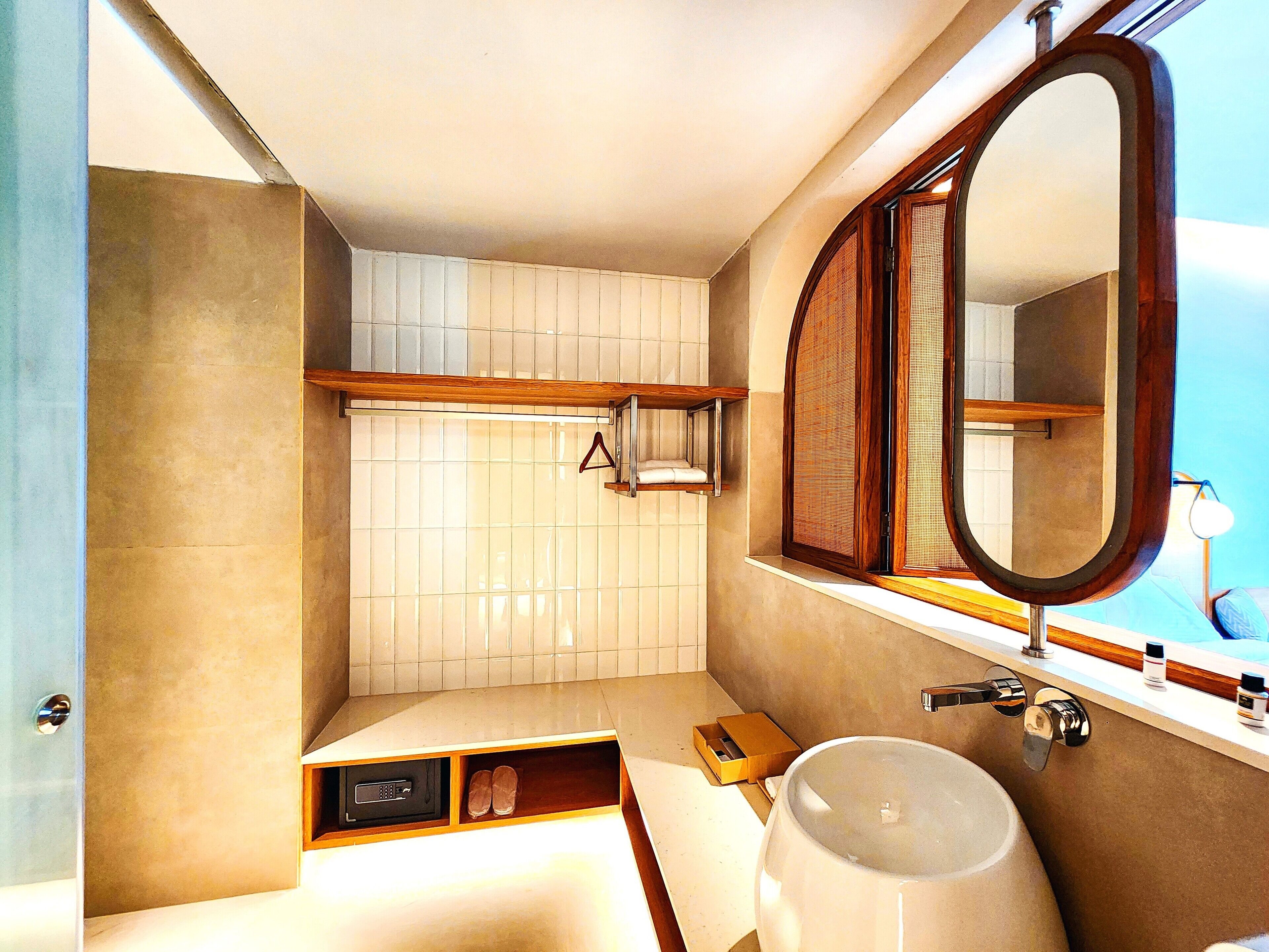 A bathroom with a large mirror, a sink, and a shower area.