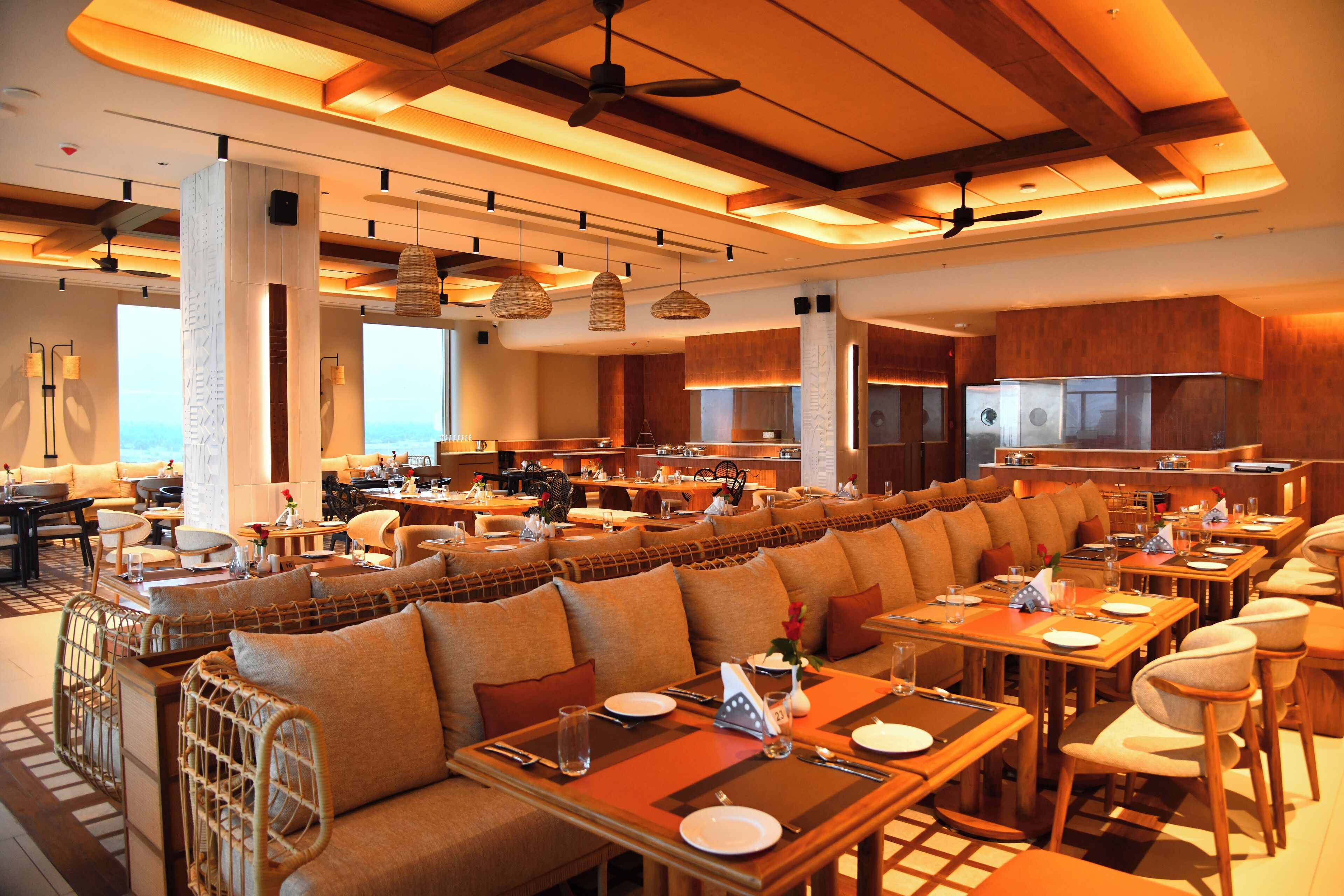 A spacious restaurant with high ceilings, wooden beams, and a long dining area with booths and tables.