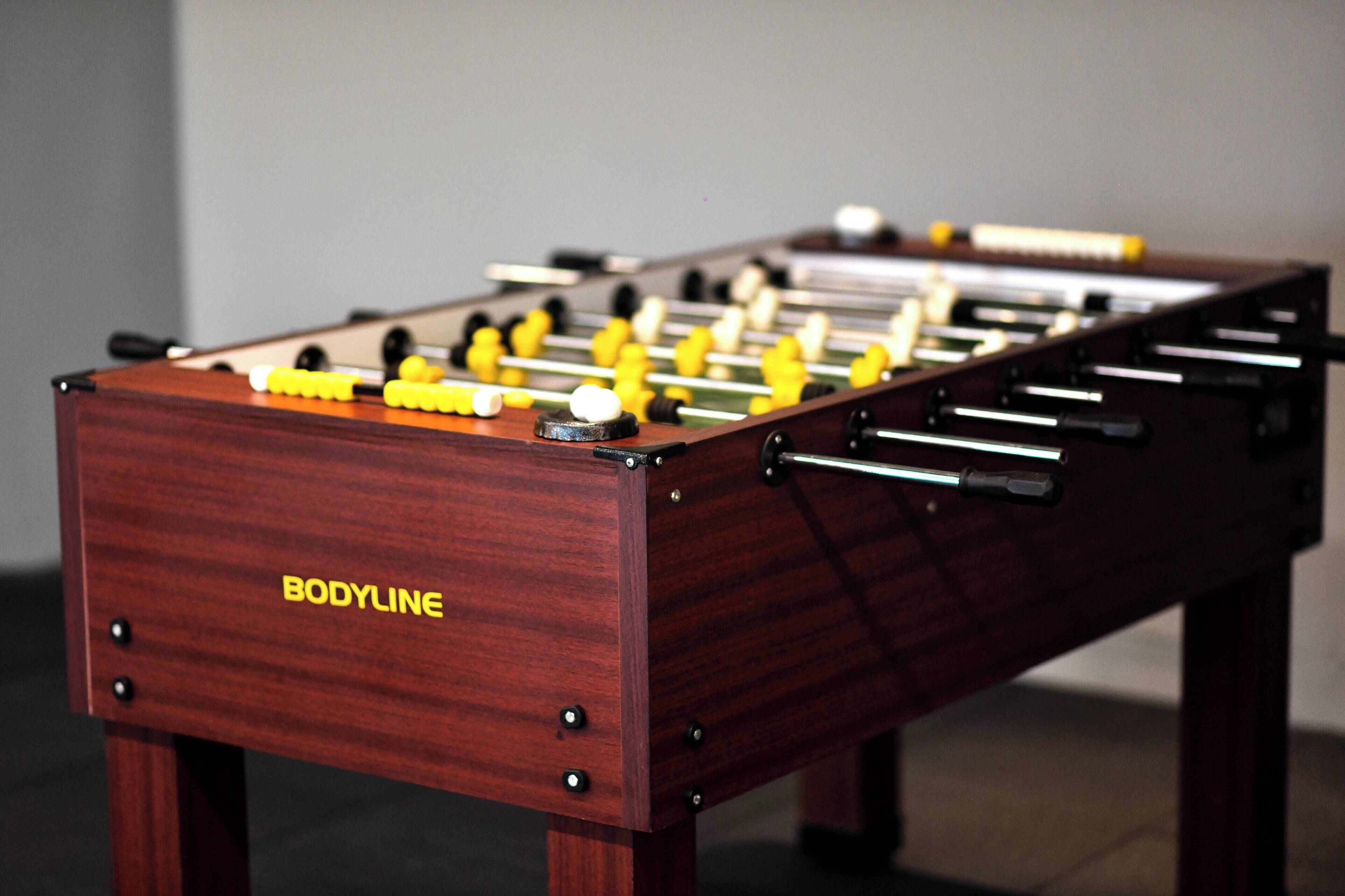 A wooden foosball table with the brand name "BODYLINE" on the side.