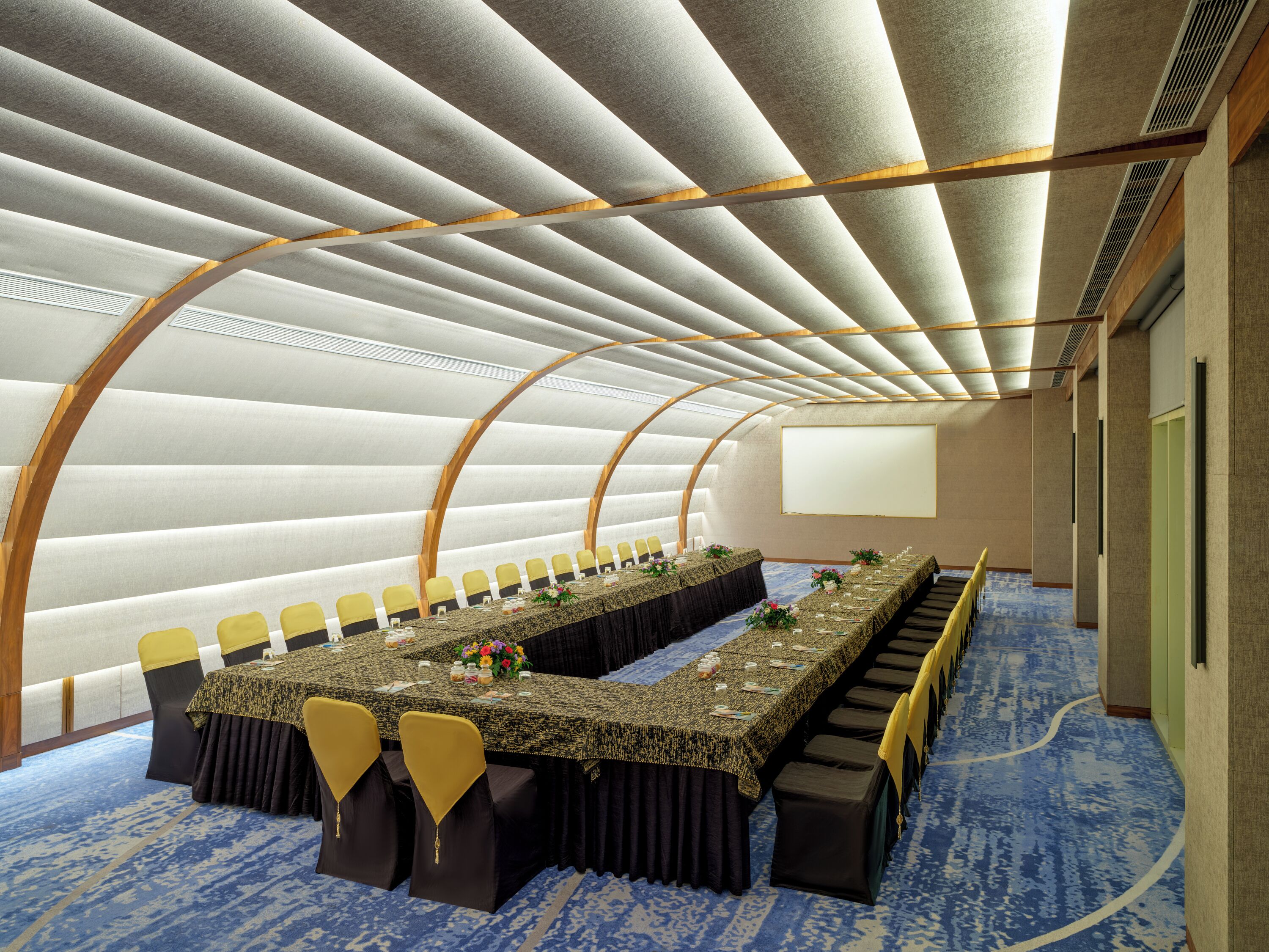 A conference room with a long table, chairs, and a projector screen.
