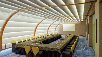 A conference room with a long table, chairs, and a projector screen.
