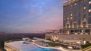 A modern hotel with a rooftop infinity pool, outdoor seating, and a view of the cityscape. - Swosti Premium Beach Resorts Puri (Brahmagiri)