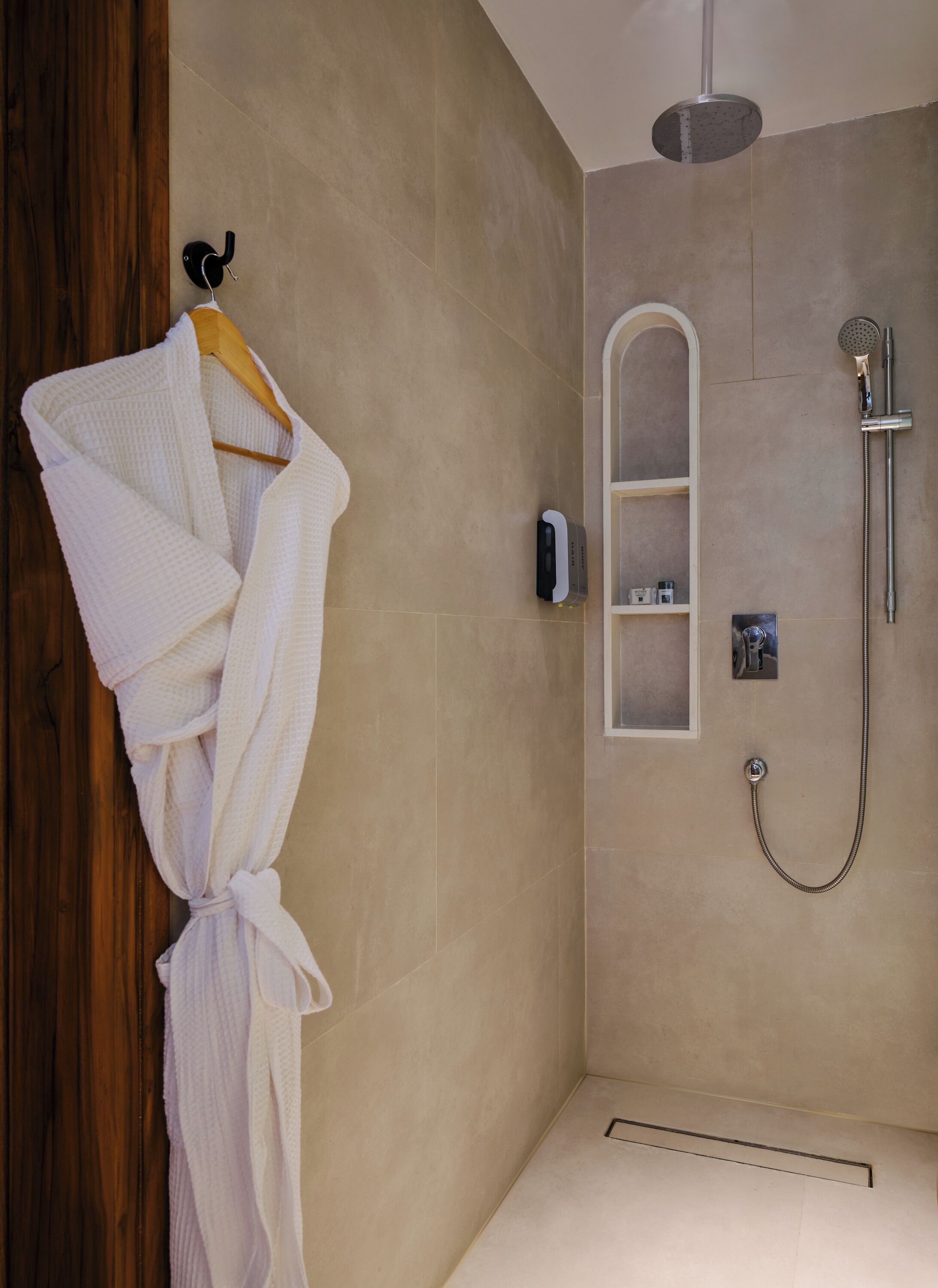 Un baño moderno con cabina de ducha, un perchero y un pequeño estante.