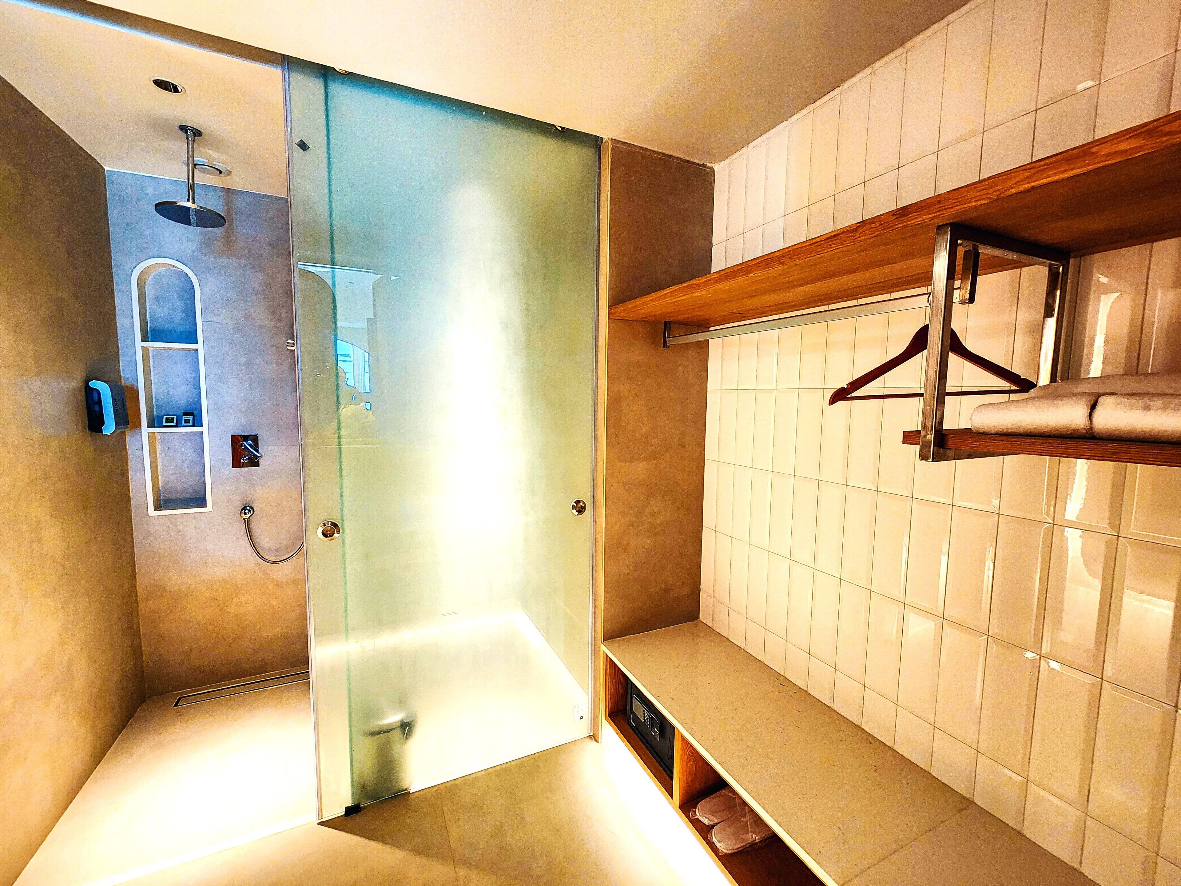 Un bany modern amb una dutxa de vidre, un lavabo integrat i una prestatgeria de fusta amb un assecador de tovalloles.