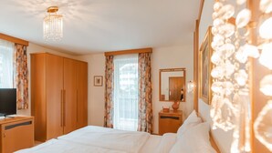 Habitación de hotel con una cama grande, un armario de madera, un televisor en una mesita auxiliar y un espejo en la pared.