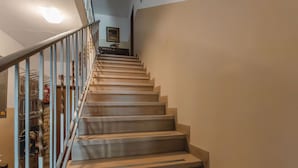 A staircase with a handrail, leading to a landing with a framed picture.