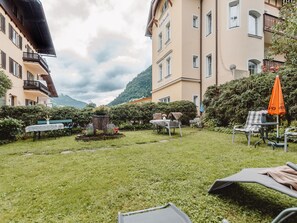 Ein Innenhof mit Außenbestuhlung, einem Brunnen und einem Berg im Hintergrund.
