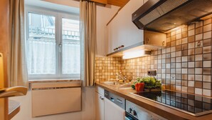 Eine moderne Küche mit Fenster, weißen Schränken, einem Herd und einer gefliesten Spritzschutzwand.