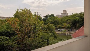 Ein Balkon mit Blick auf ein historisches Gebäude, Bäume und ein Gewässer.