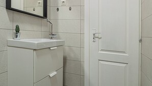 Ein Badezimmer mit einem weißen Waschbecken, einem Spiegel und einer Tür.
