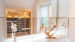 Ein modernes Badezimmer mit Duschkabine aus Glas, einem weißen Waschbecken mit Dekoration und einem Fenster mit Jalousien.