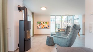 Ein modernes Wohnzimmer mit integriertem Kamin, bequemen Sitzmöglichkeiten und einem großen Fenster mit Blick ins Freie.