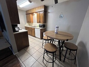 A compact kitchen with wooden cabinets, a round dining table, and two stools. - Affordable & Cozy Near the Base is set in Lawton. Both free WiFi and parking on-site are accessible at the apartment free of charge! (Lawton)