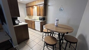 A compact kitchen with wooden cabinets, a round dining table, and two stools. - Affordable & Cozy Near the Base is set in Lawton. Both free WiFi and parking on-site are accessible at the apartment free of charge! (Lawton)