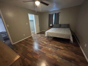 A bedroom with a bed, a ceiling fan, a door, and a window with curtains. - Affordable & Cozy Near the Base is set in Lawton. Both free WiFi and parking on-site are accessible at the apartment free of charge! (Lawton)