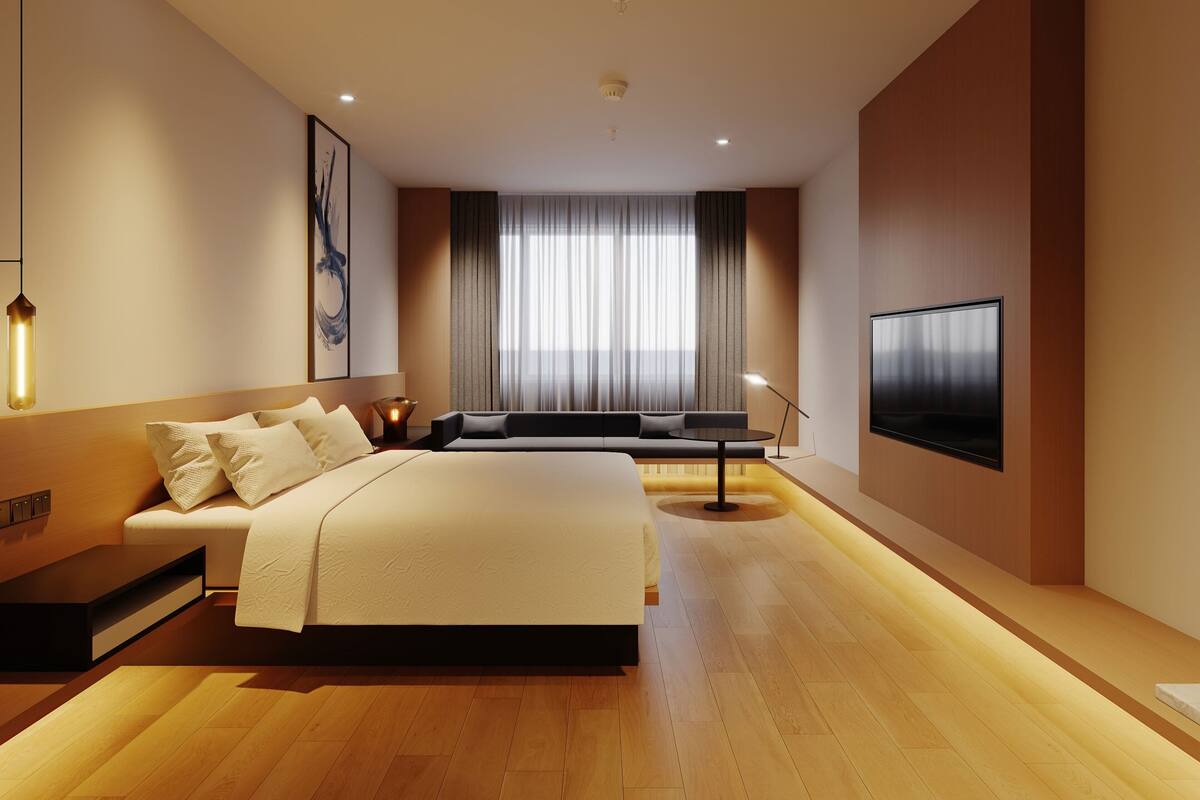 Ein modernes Schlafzimmer mit einem großen Bett, einem Flachbildfernseher und einem Sofa.