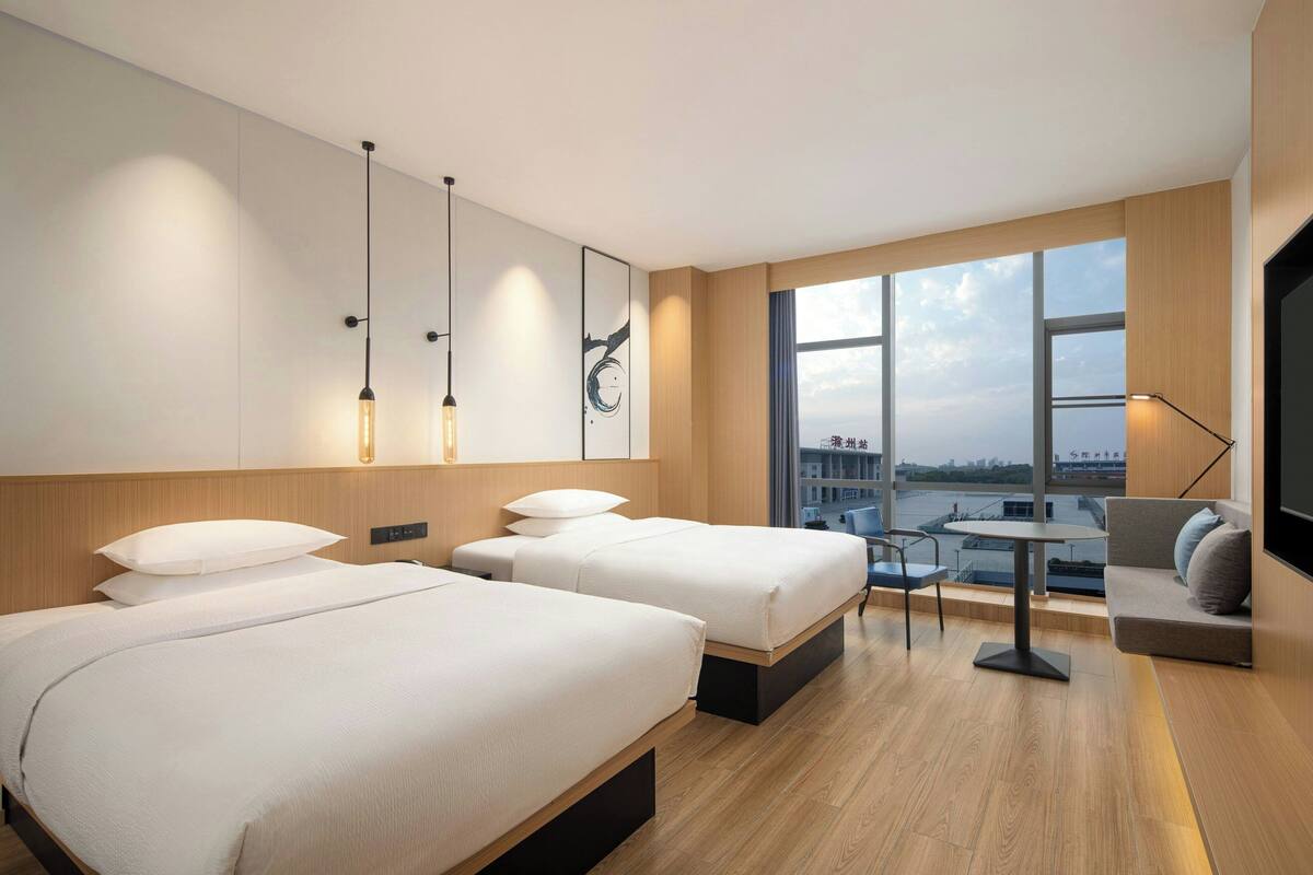 Ein modernes Hotelzimmer mit zwei Betten, einem kleinen Tisch und einer Couch.