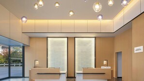 A modern reception area with two reception desks, a large window, and pendant lighting. - Fairfield by Marriott Chuzhou Railway Station (Chuzhou)