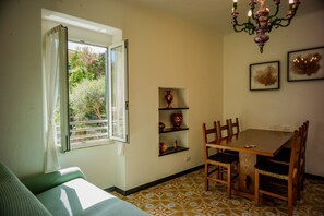 Un espace repas comprenant une table et des chaises, un lustre et des étagères ornées d’objets décoratifs.