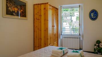 Une chambre à coucher avec un lit, une armoire en bois, une fenêtre donnant sur un beau paysage et un tableau encadré au mur.