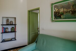Ein Zimmer mit grüner Tür, einem grünen Sofa und einem Regal mit Dekoration.