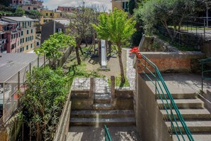 Steinstufen führen zu einem Gartenbereich mit einem kleinen Baum und einer weißen Struktur.