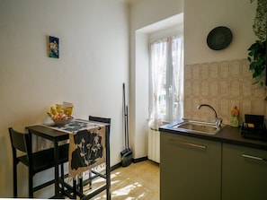 Une cuisine de taille réduite comprenant une table à manger, des chaises, un évier et une fenêtre avec des rideaux.