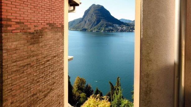 Une vue depuis un balcon donnant sur un lac, avec une montagne en arrière-plan.