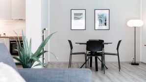 Un salon moderne avec un coin repas, comprenant un canapé gris, une table à manger avec des chaises noires et un lampadaire.