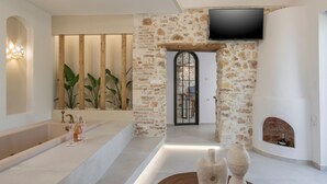 Un baño moderno con pared de piedra, una bañera grande y un televisor de pantalla plana sobre una chimenea.