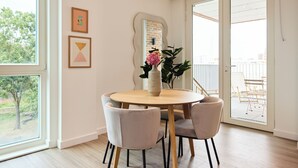 A dining area with a round table, four chairs, a vase with flowers, and a large window. - The Tottenham Escape - Lovely 2bdr Flat With Balcony (London)
