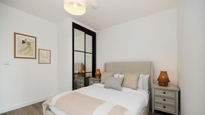 A bedroom with a large bed, bedside tables, a nightstand, and wall art. - The Tottenham Escape - Lovely 2bdr Flat With Balcony (London)
