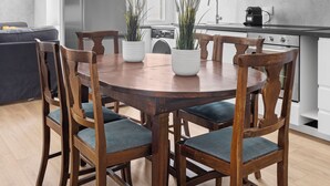 A modern kitchen with a round wooden table, four chairs, and a potted plant. - Sunny House Gianicolo (roma)