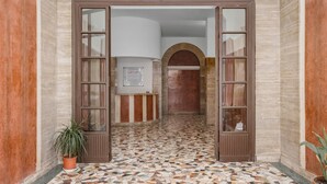 A hallway with a tiled floor leading to a room with a window and a door. - Sunny House Gianicolo (roma)