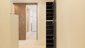 A hallway with a wooden door, a white refrigerator, and a black shelving unit. - Sky Up Oshiage by Tranova (Tokyo)