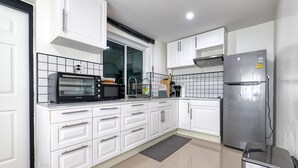 A modern kitchen with white cabinets, a stainless steel refrigerator, a built-in oven, and a window above the sink. - Happy House Samui 4 Bedrooms (Koh Samui)