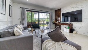 A modern living room with a sofa, a coffee table, and a TV mounted on the wall. - Happy House Samui 4 Bedrooms (Koh Samui)