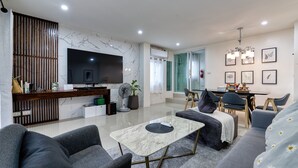 A modern living room with a flat-screen TV, a dining area with a table and chairs, and a sofa. - Happy House Samui 4 Bedrooms (Koh Samui)