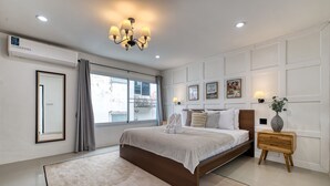 A modern bedroom with a large bed, a bedside table with a lamp, and a window with curtains. - Happy House Samui 4 Bedrooms (Koh Samui)