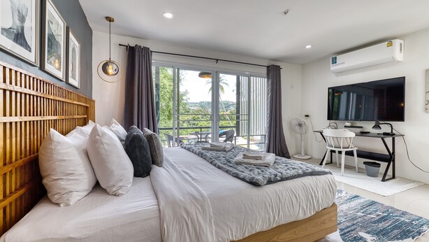 A modern bedroom with a large bed, a desk, a TV, and a view of the outdoors. - Happy House Samui 4 Bedrooms (Koh Samui)