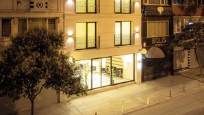 Um hotel de vários andares com varandas iluminadas e um restaurante no andar térreo.