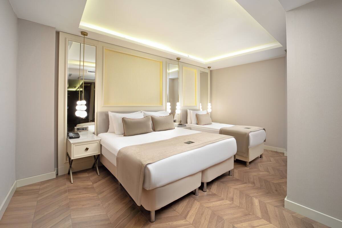 A modern hotel room with a large bed, a bedside table, a mirror, and a wardrobe.