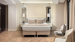 Quarto de hotel moderno com uma cama grande, mesas de cabeceira, uma cadeira e um espelho.